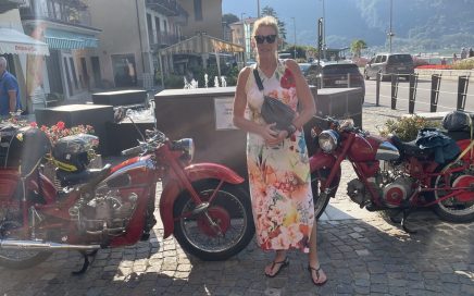 Femke in een zonnig Porlezza voor twee rode Moto Guzzi's.